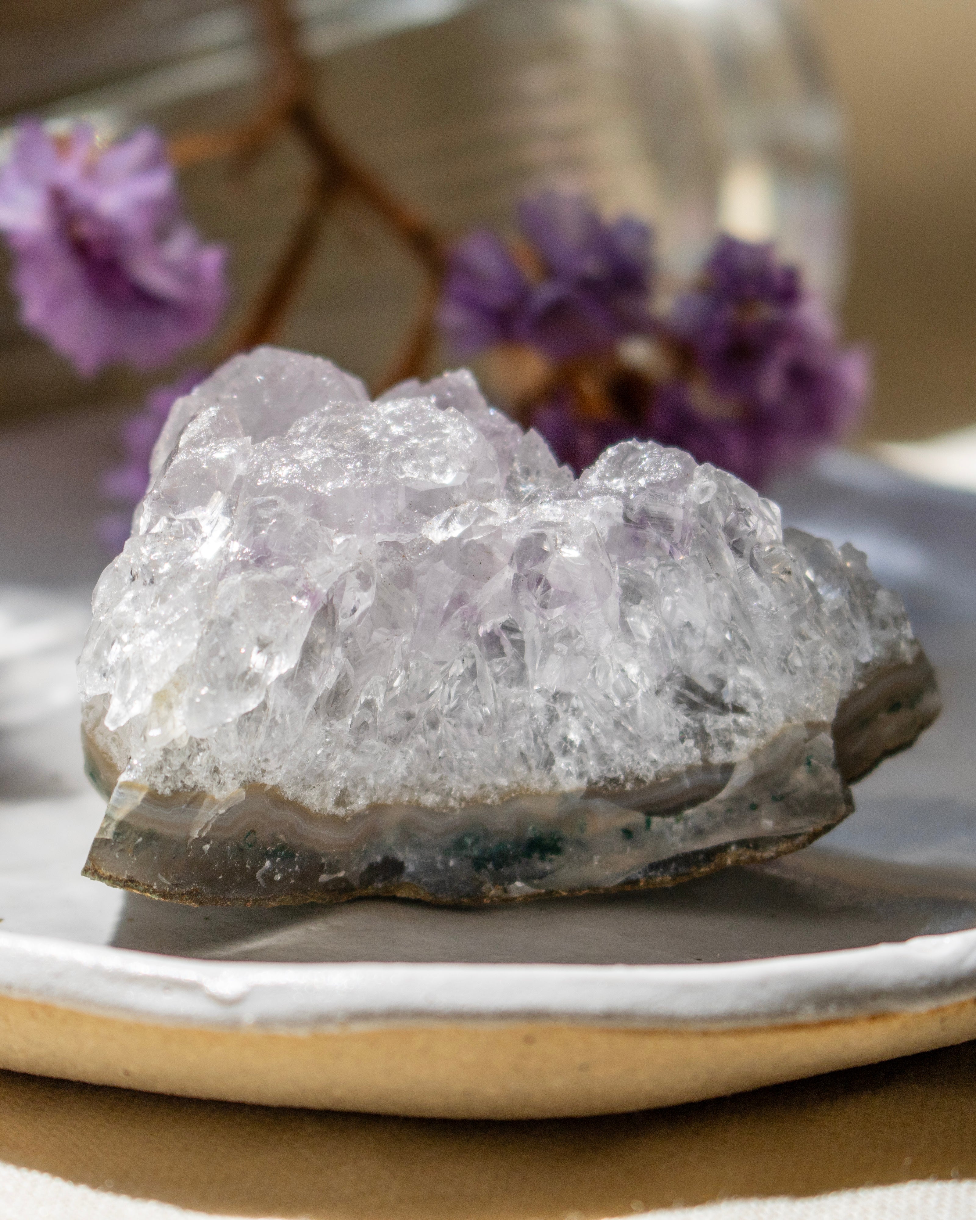 Crystal rock on a plate with blurred purple flowers in the background