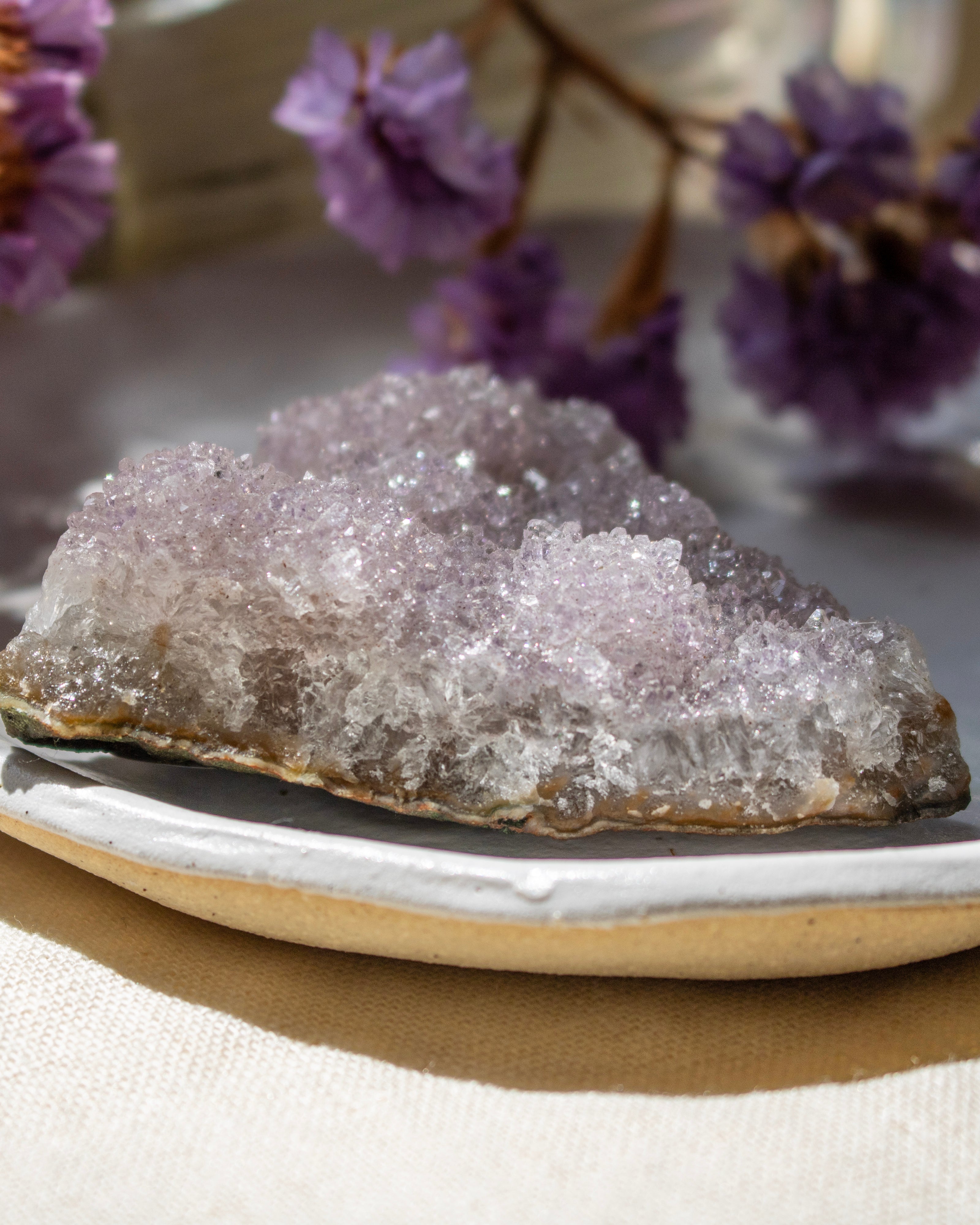 Crystal rock on a white plate with purple flowers in the background