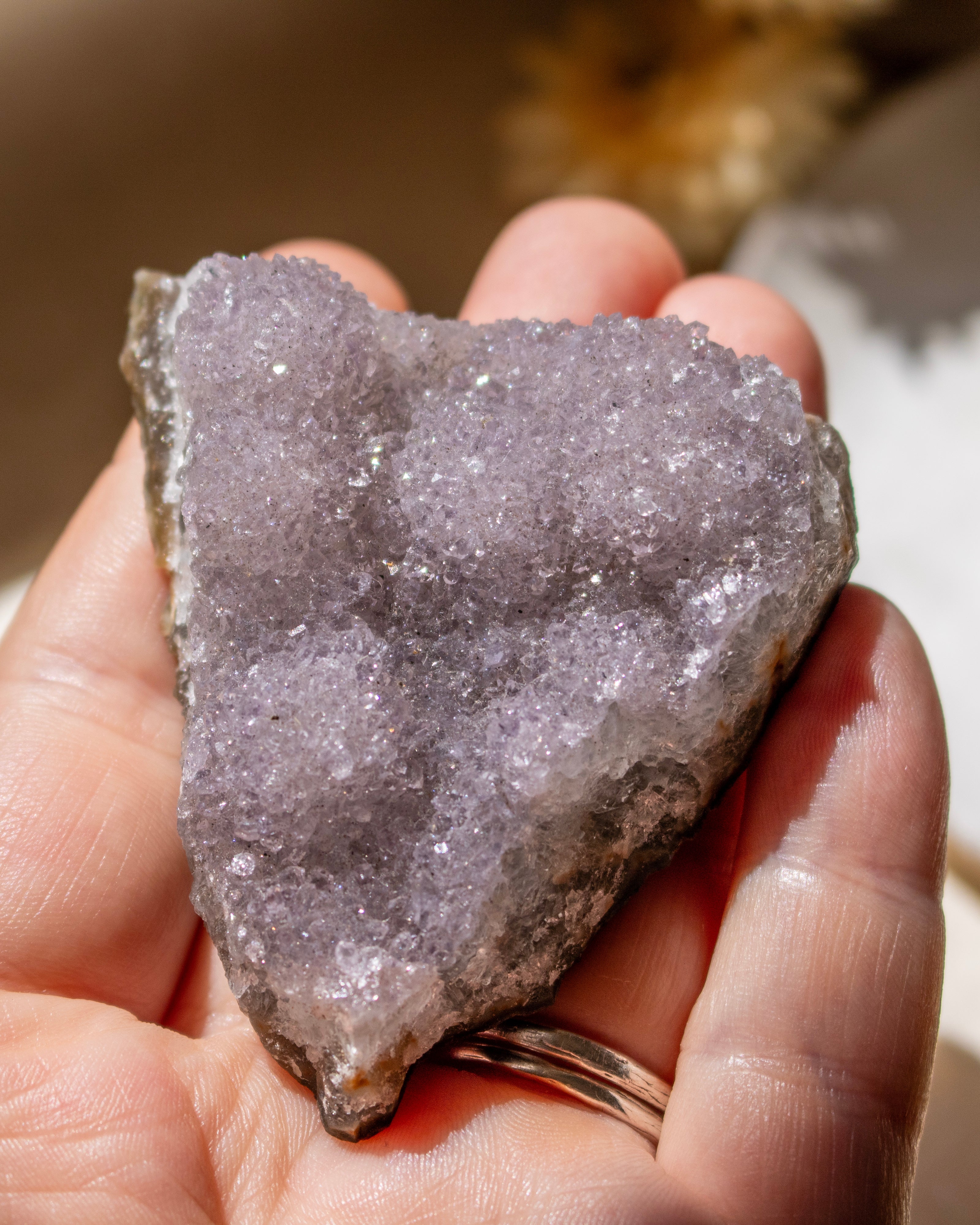 Hand holding a large crystal rock with a blurred natural background