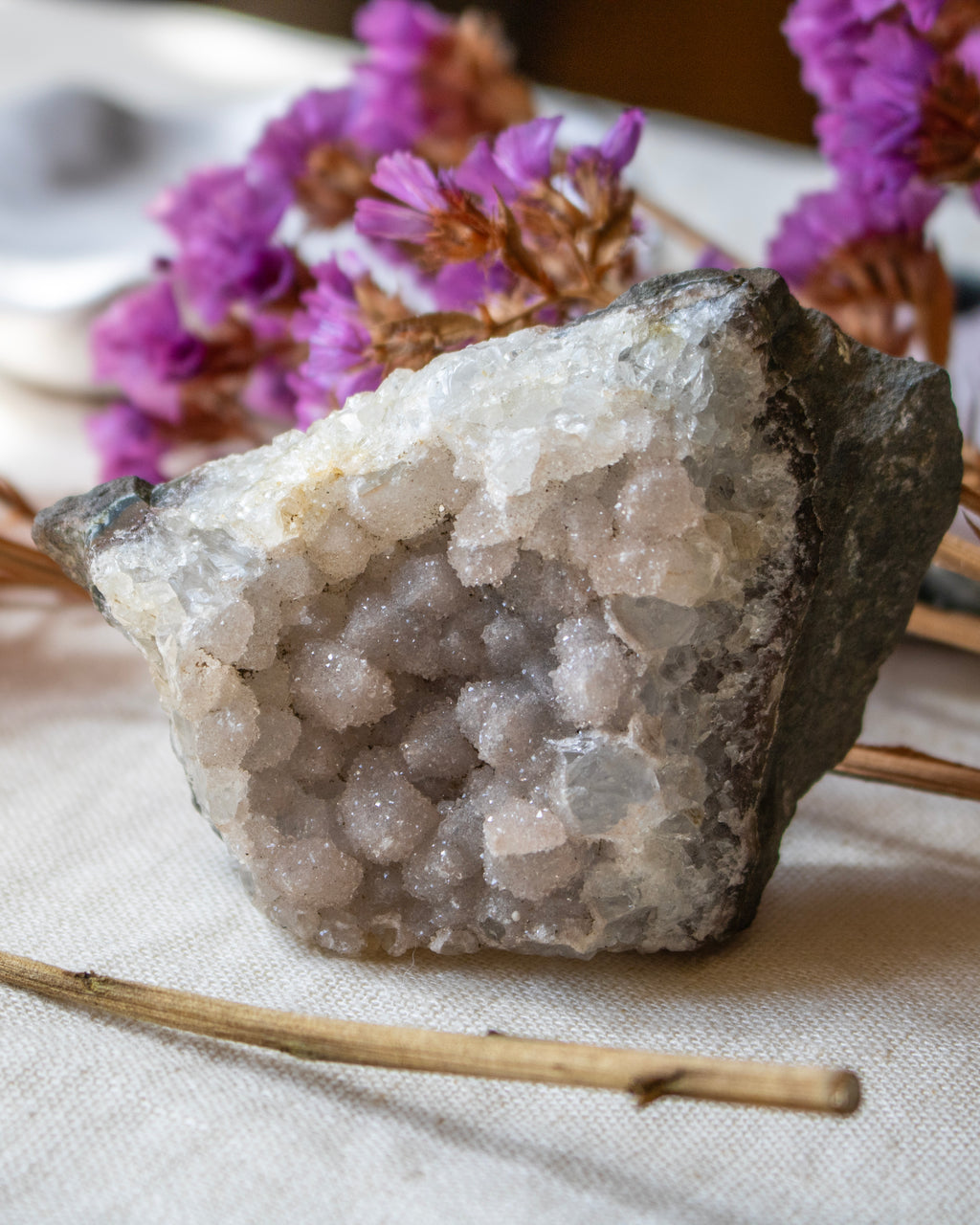 Crystal rock with purple flowers on a textured surface