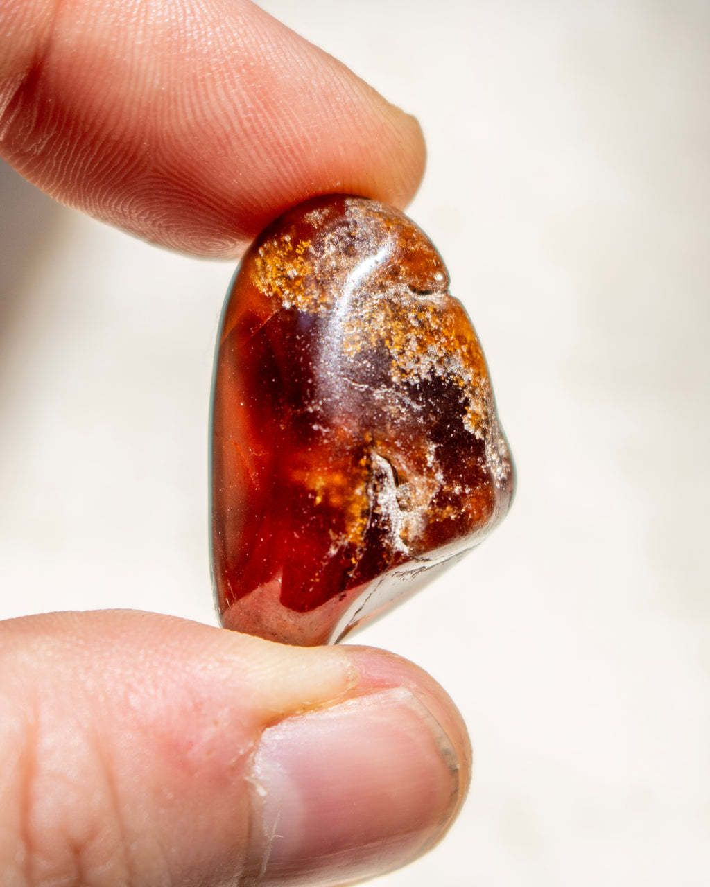 Raw amber stone held between fingers against a neutral background