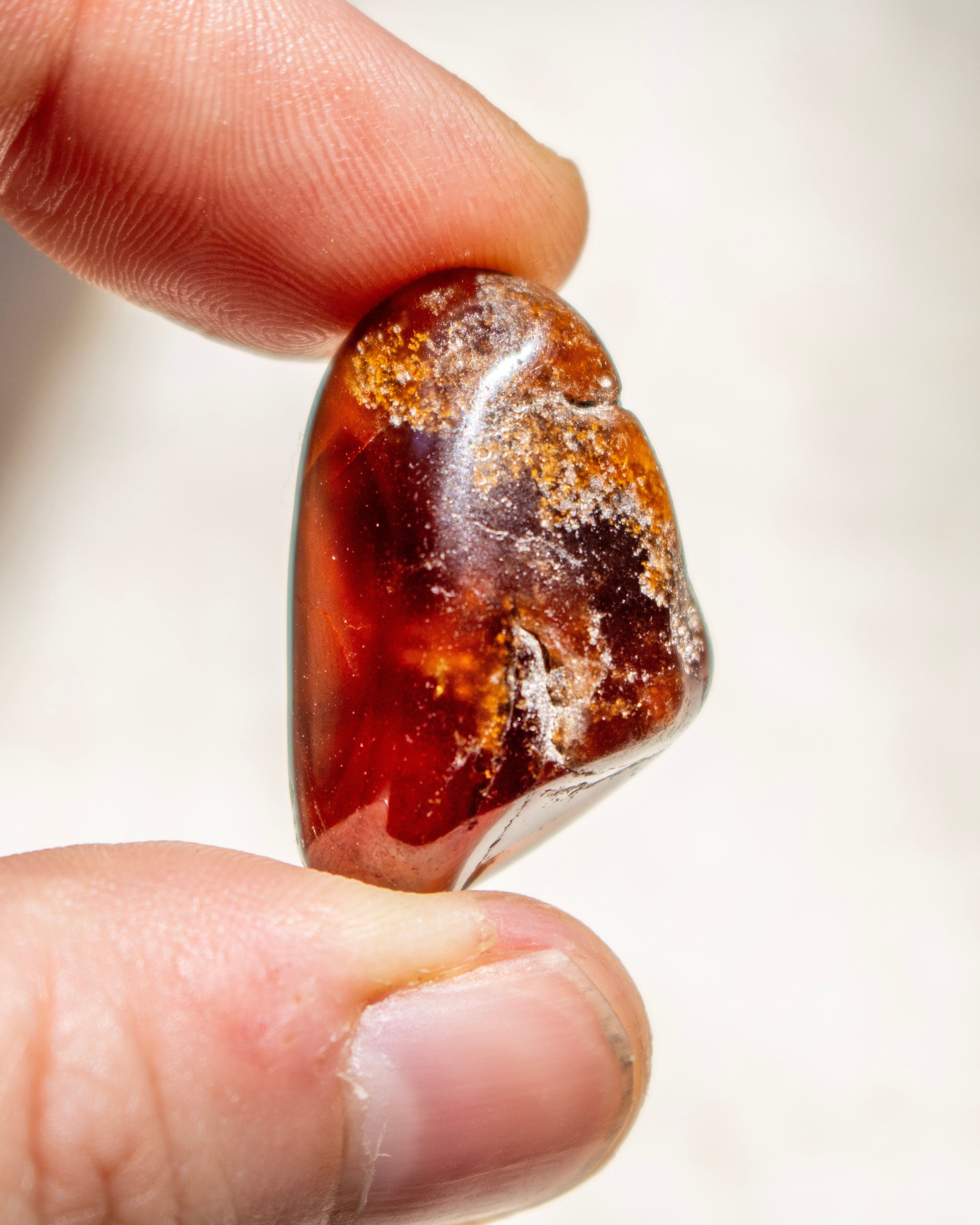 Raw amber stone held between fingers against a neutral background