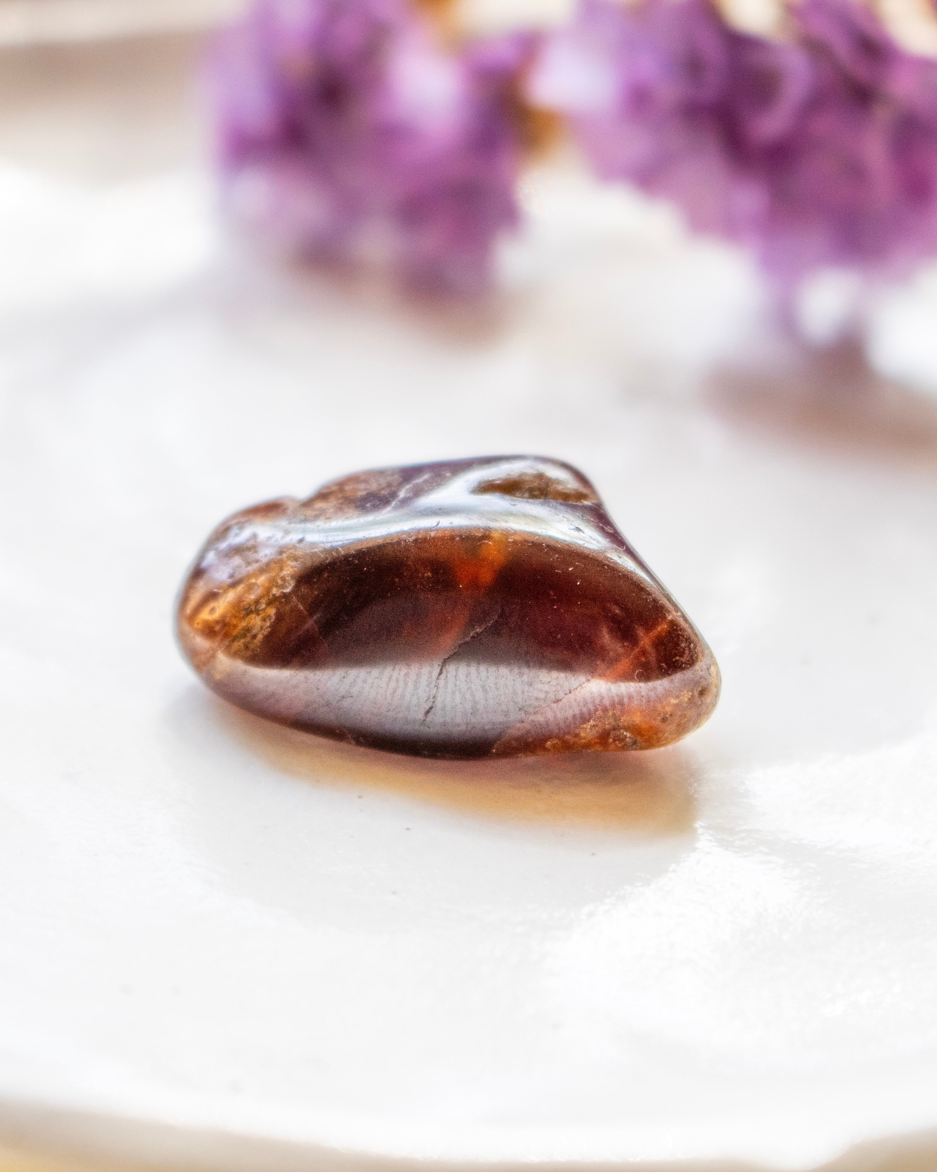 Brown stone on a white surface with purple flowers in the background