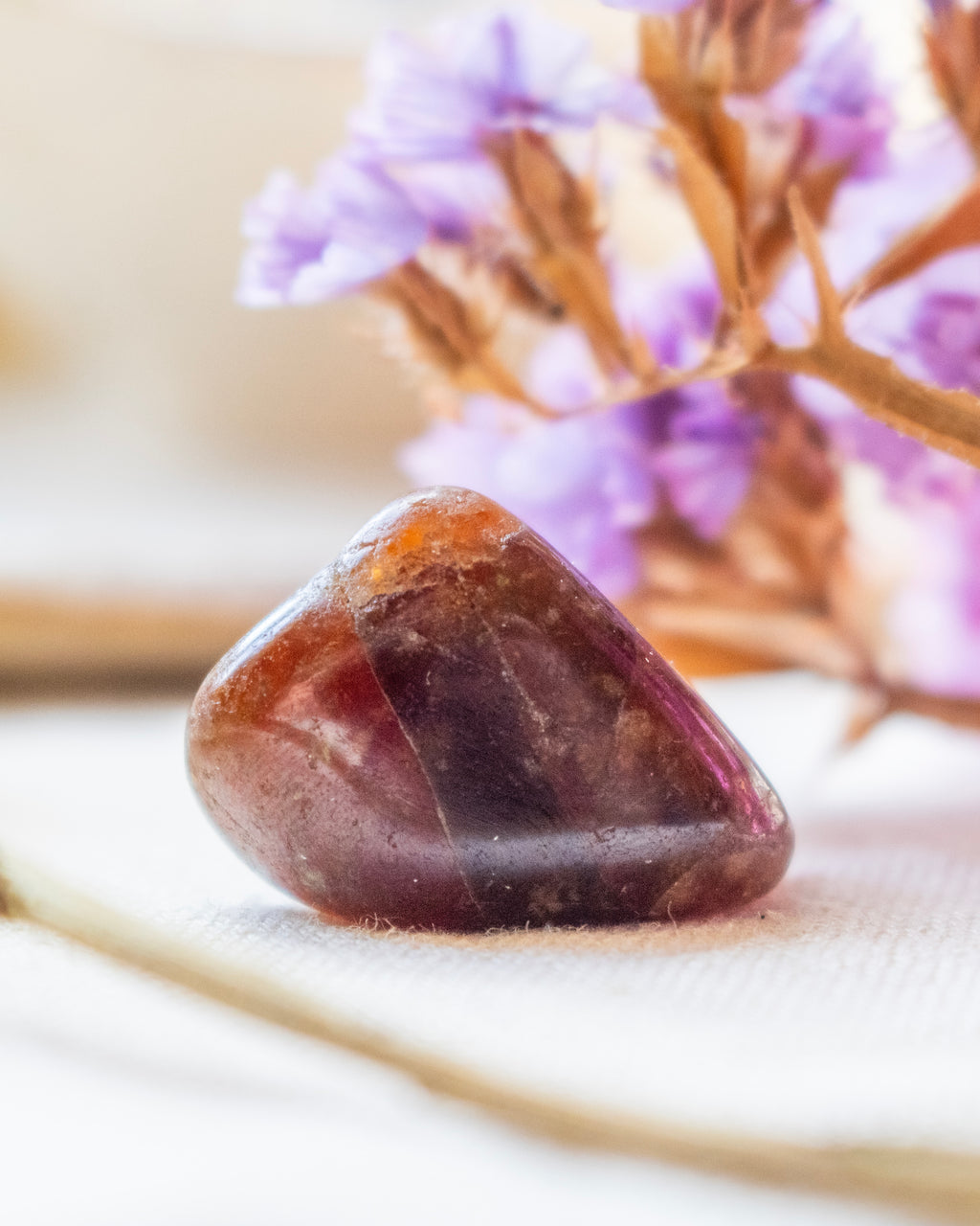 Brown stone on a white surface with blurred purple flowers in the background