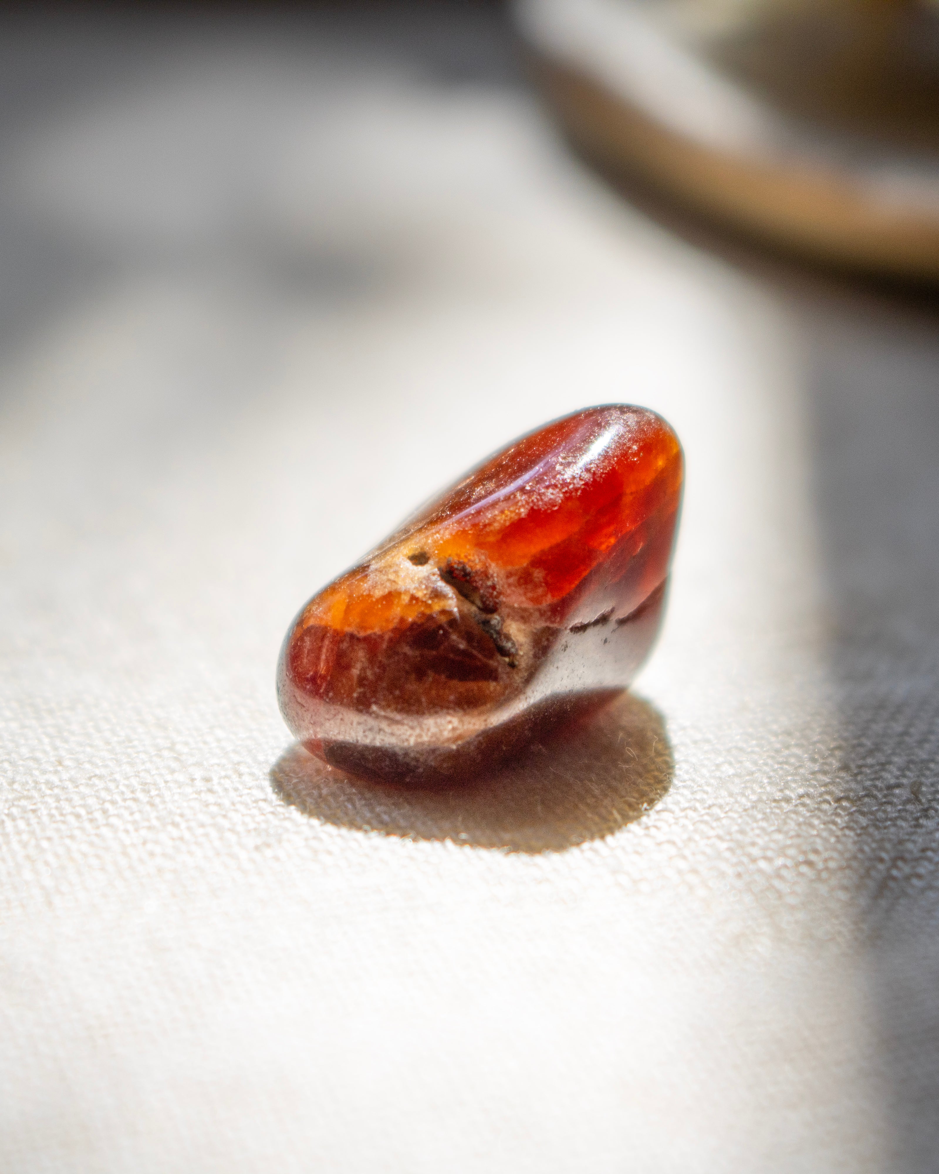 Close-up of a polished amber stone on a textured surface