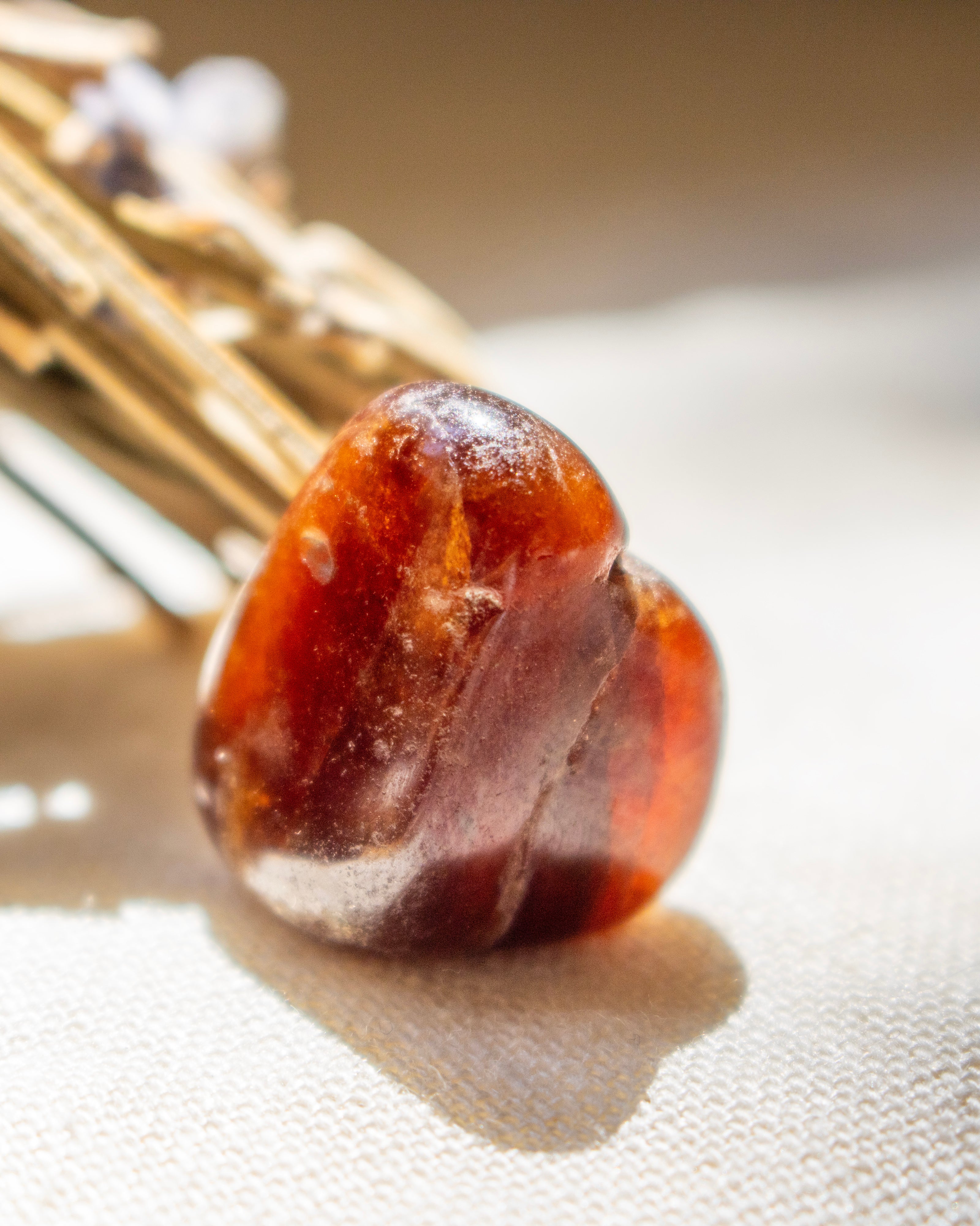 Close-up of a amber stone on a textured surface with a blurred background