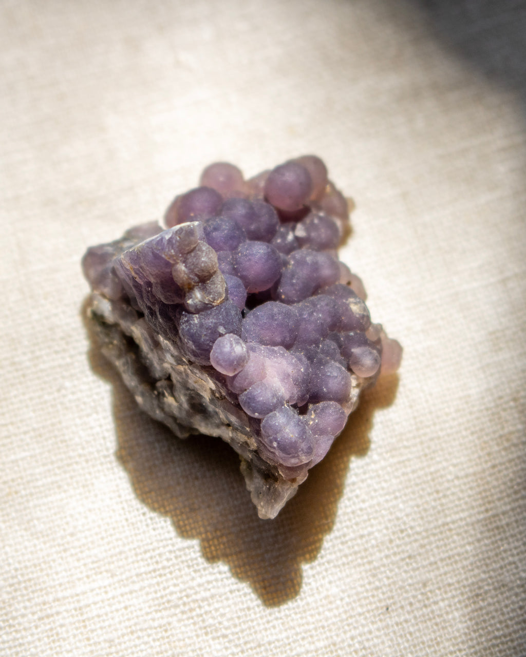 Purple crystal cluster on a beige surface