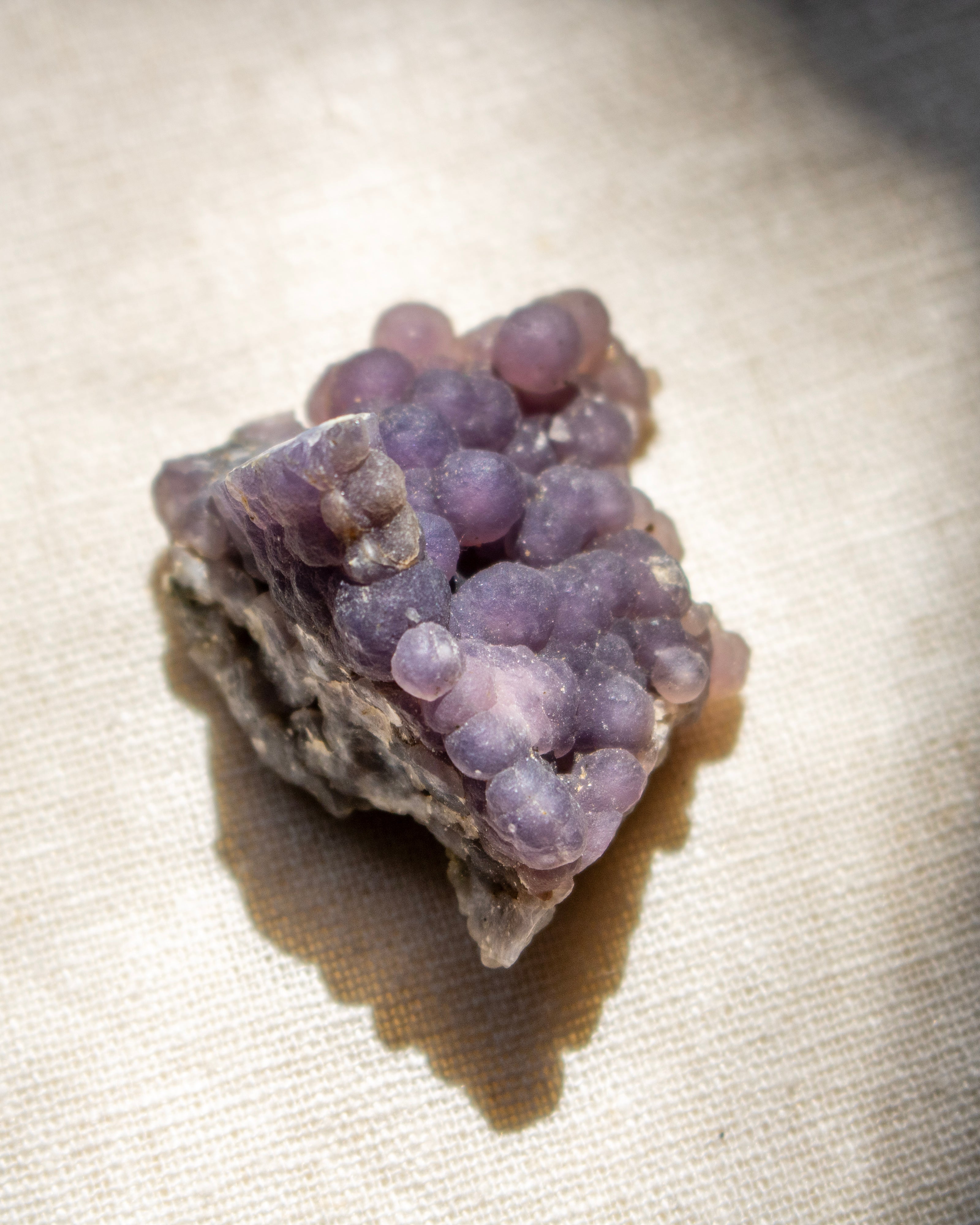 Purple crystal cluster on a beige surface