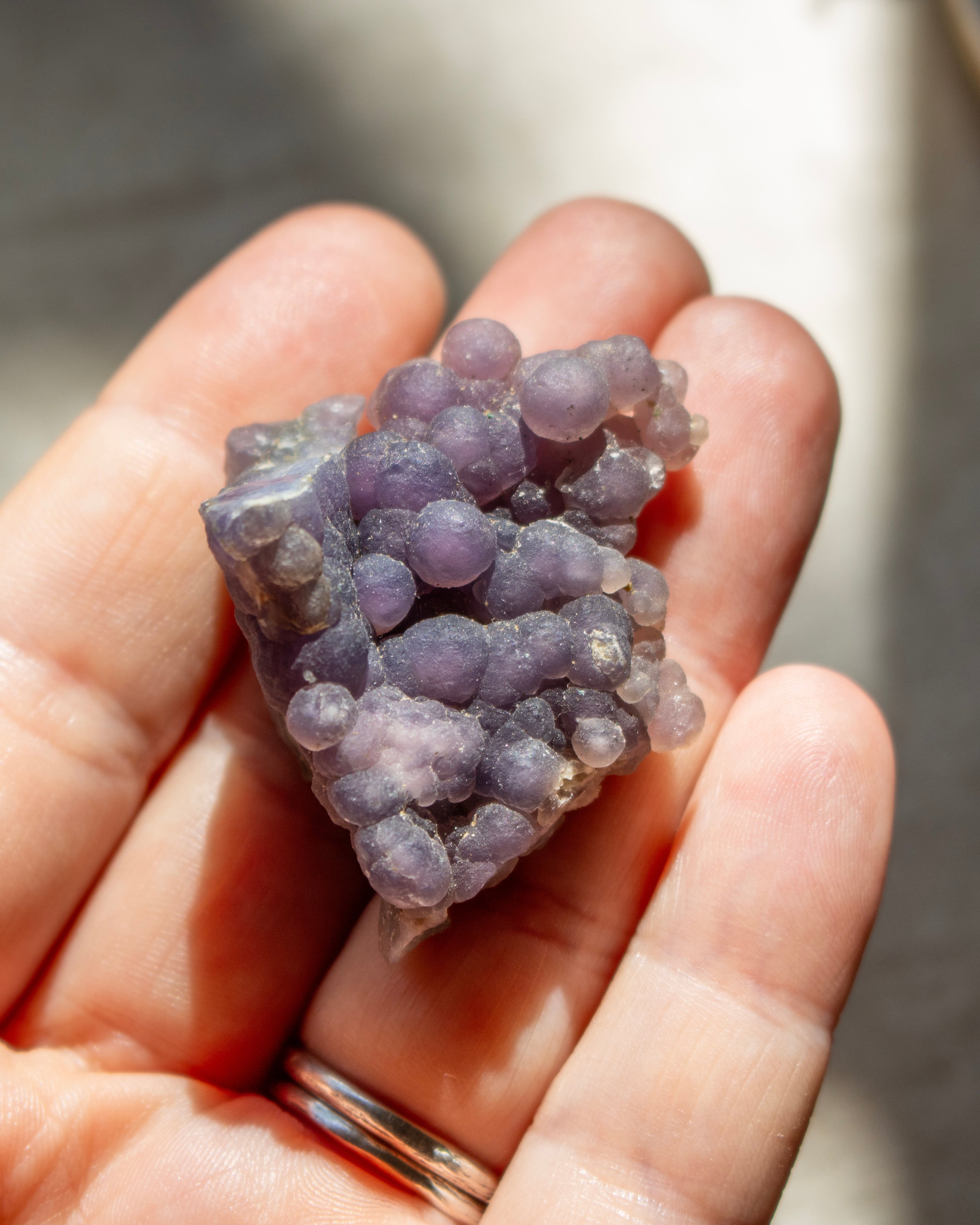 Hand holding a cluster of purple crystals against a blurred background