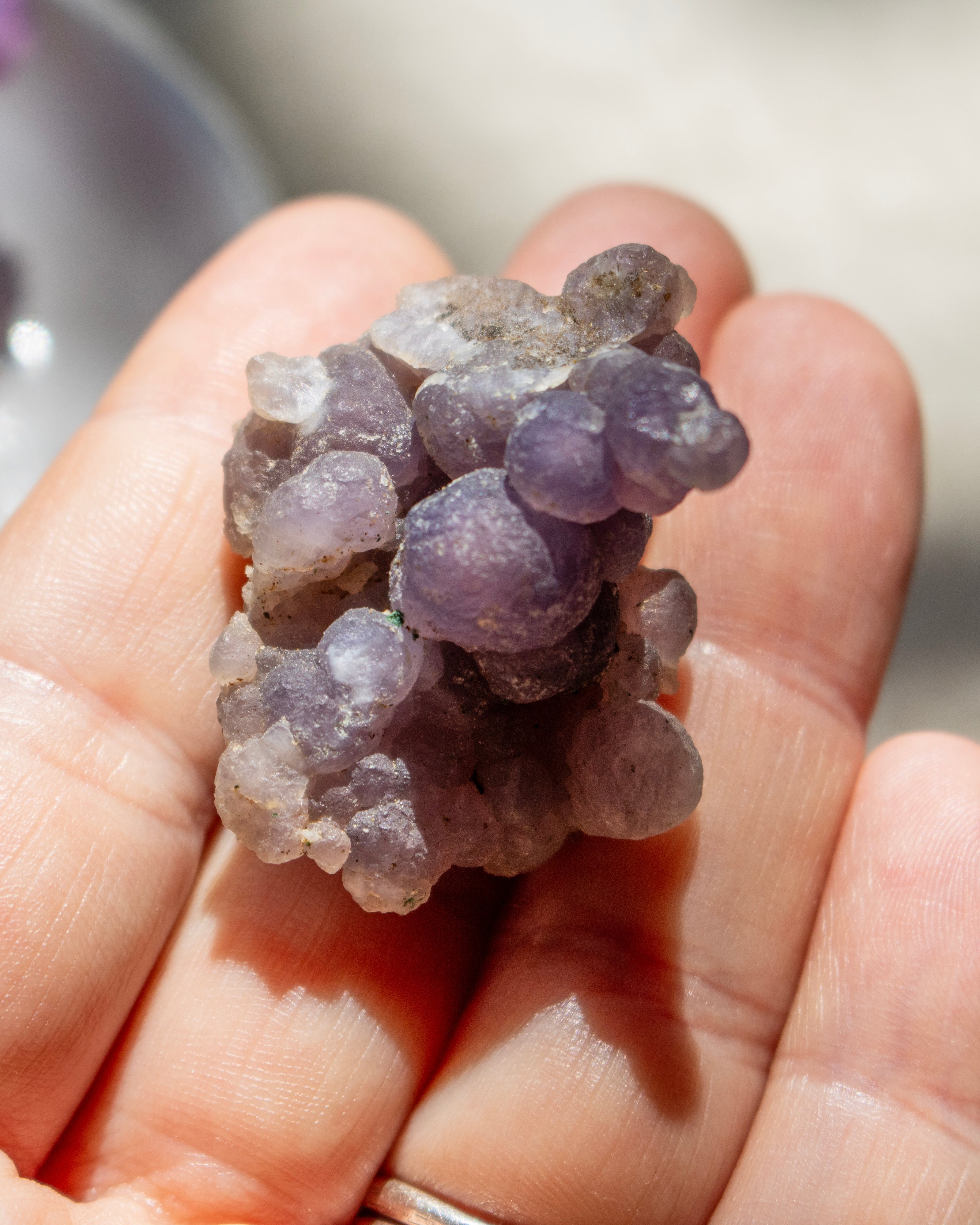 Hand holding a cluster of purple crystal-like rocks.
