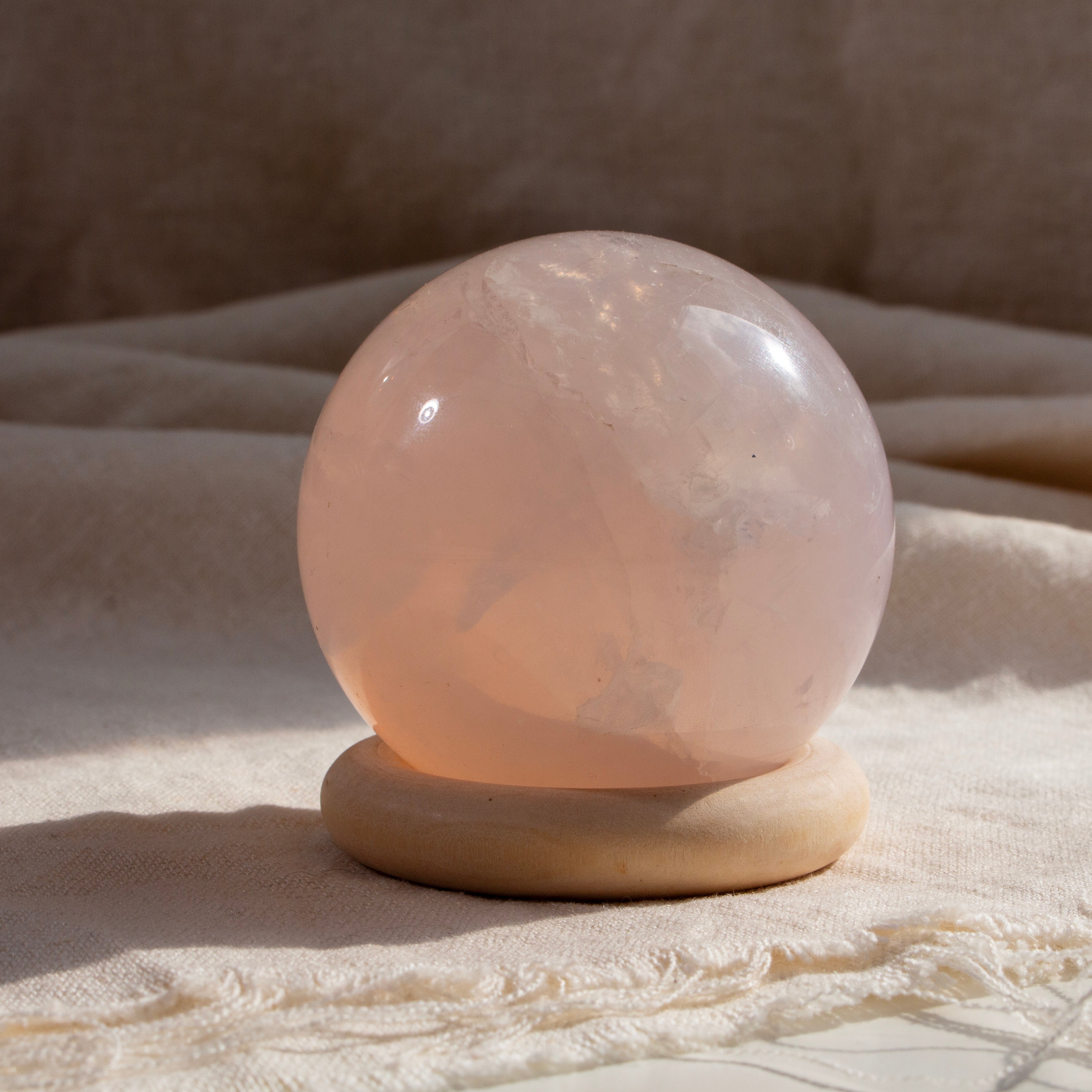 Rose quartz crystal ball on a beige fabric background