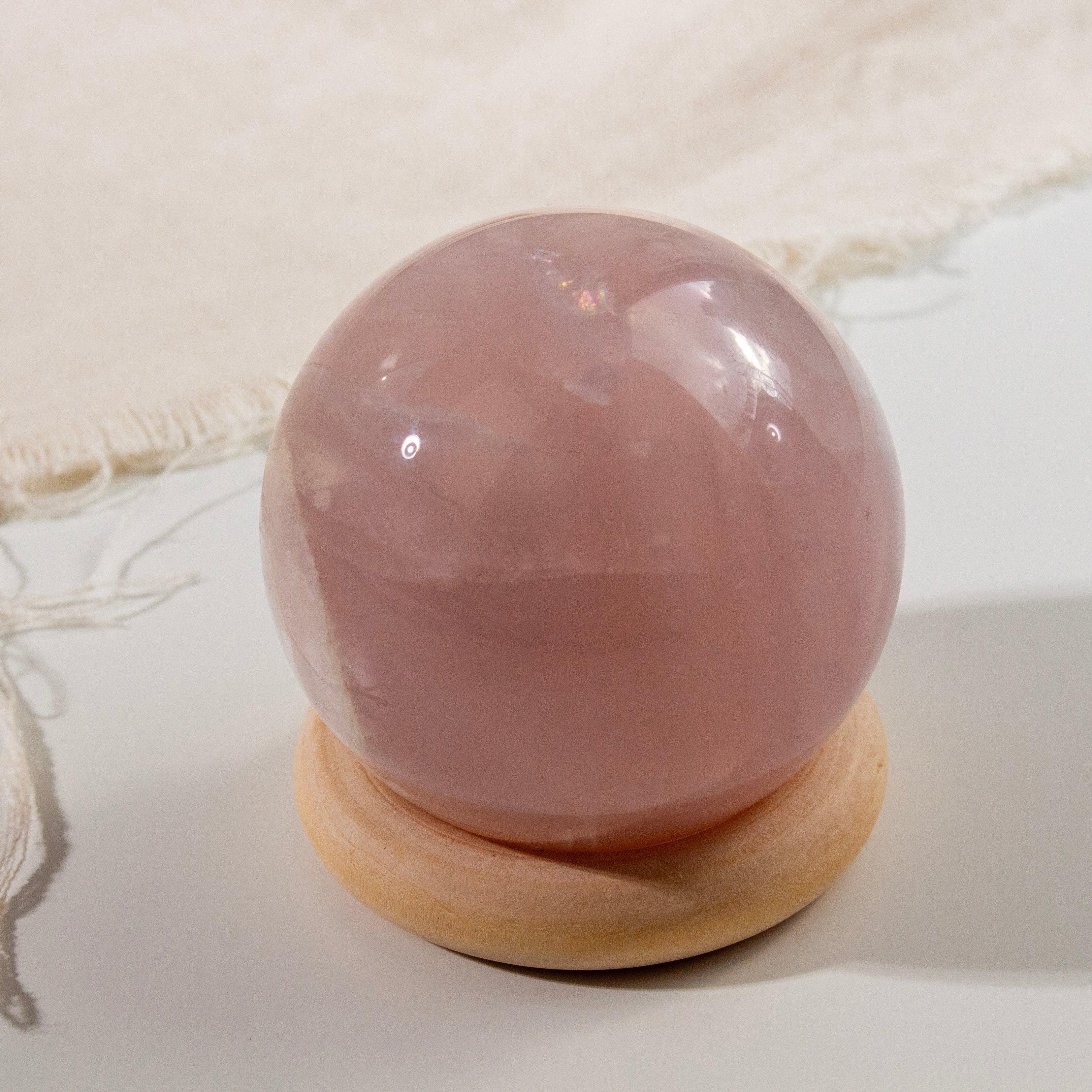 Pink crystal ball on a wooden stand with a white background