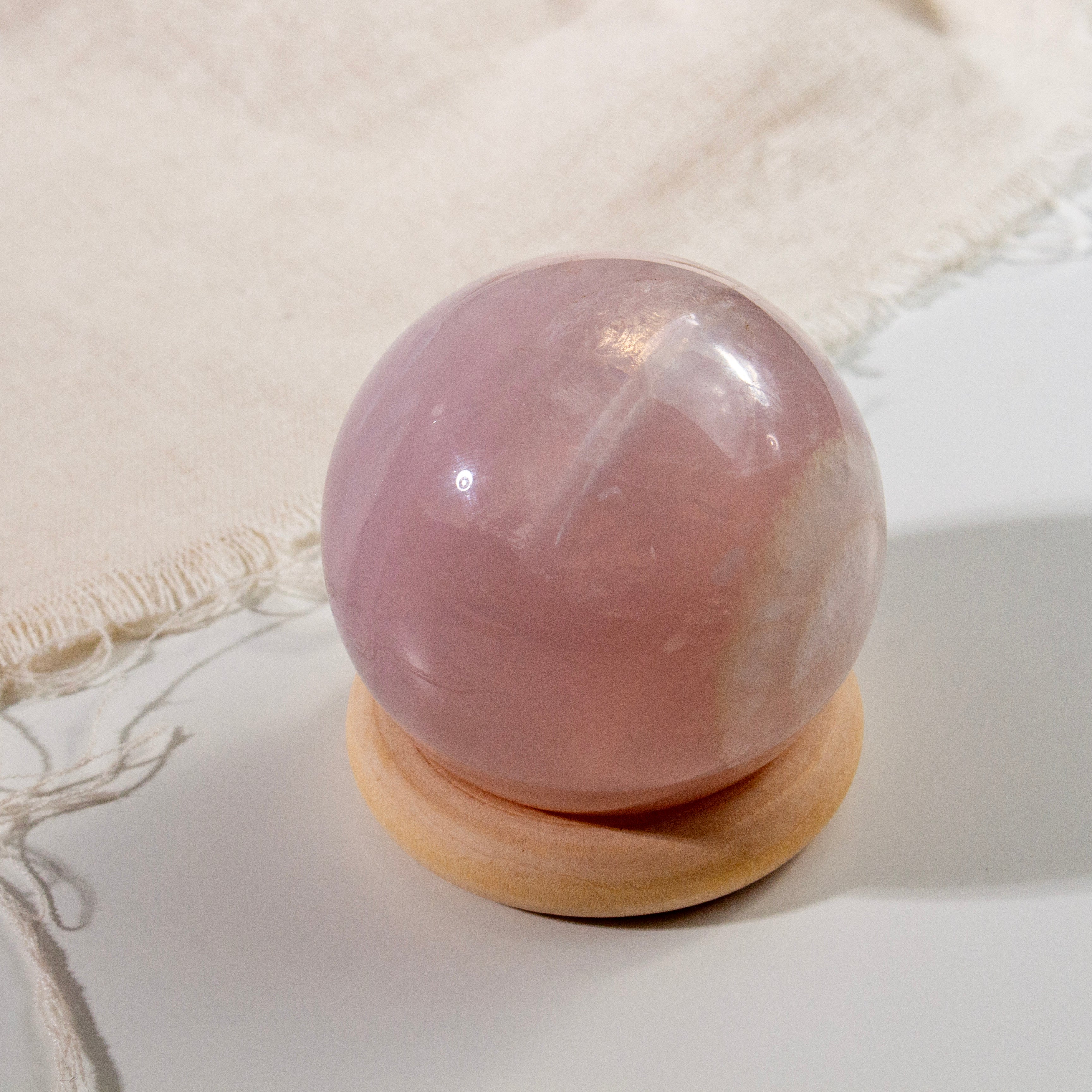 Pink crystal ball on a wooden stand with a white fabric background