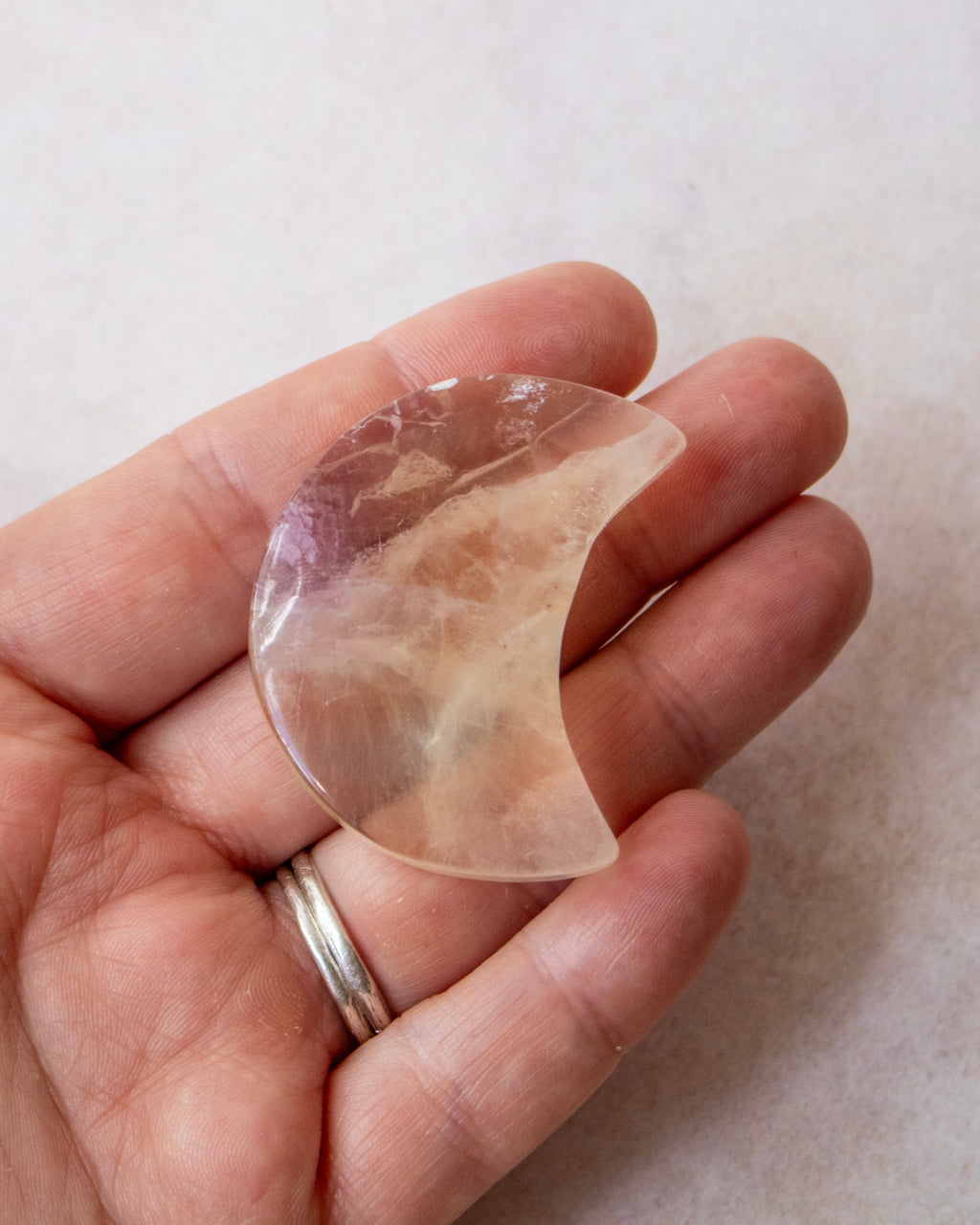 a clear crystal stone in the shape of a crescent moon being held in the palm of a hand