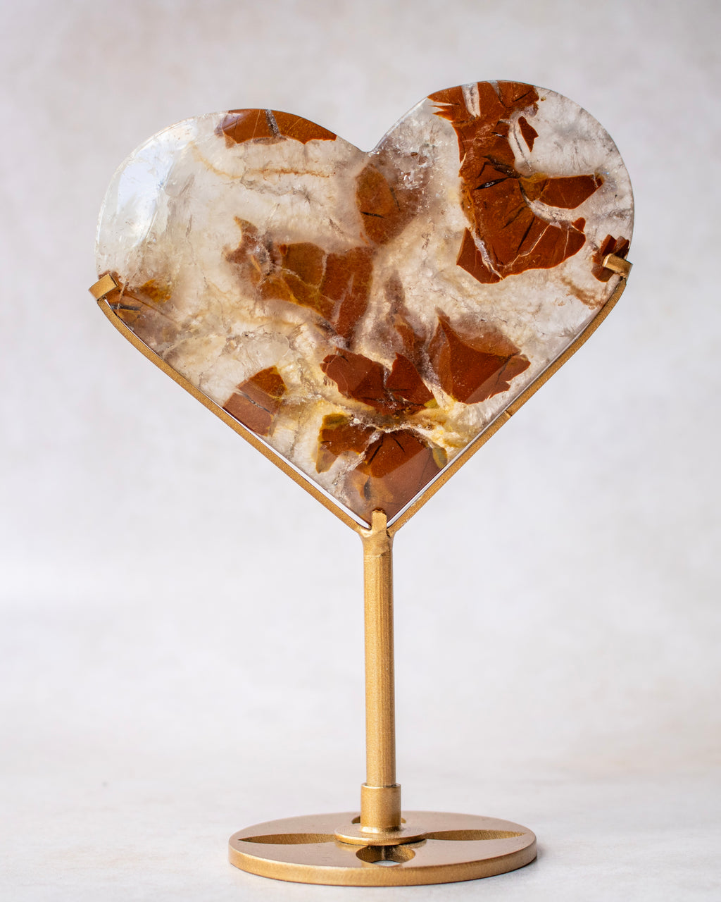 Heart-shaped stone tabletop decor with a brown and cream marbled pattern, mounted on a gold-finished metal stand with a round base.