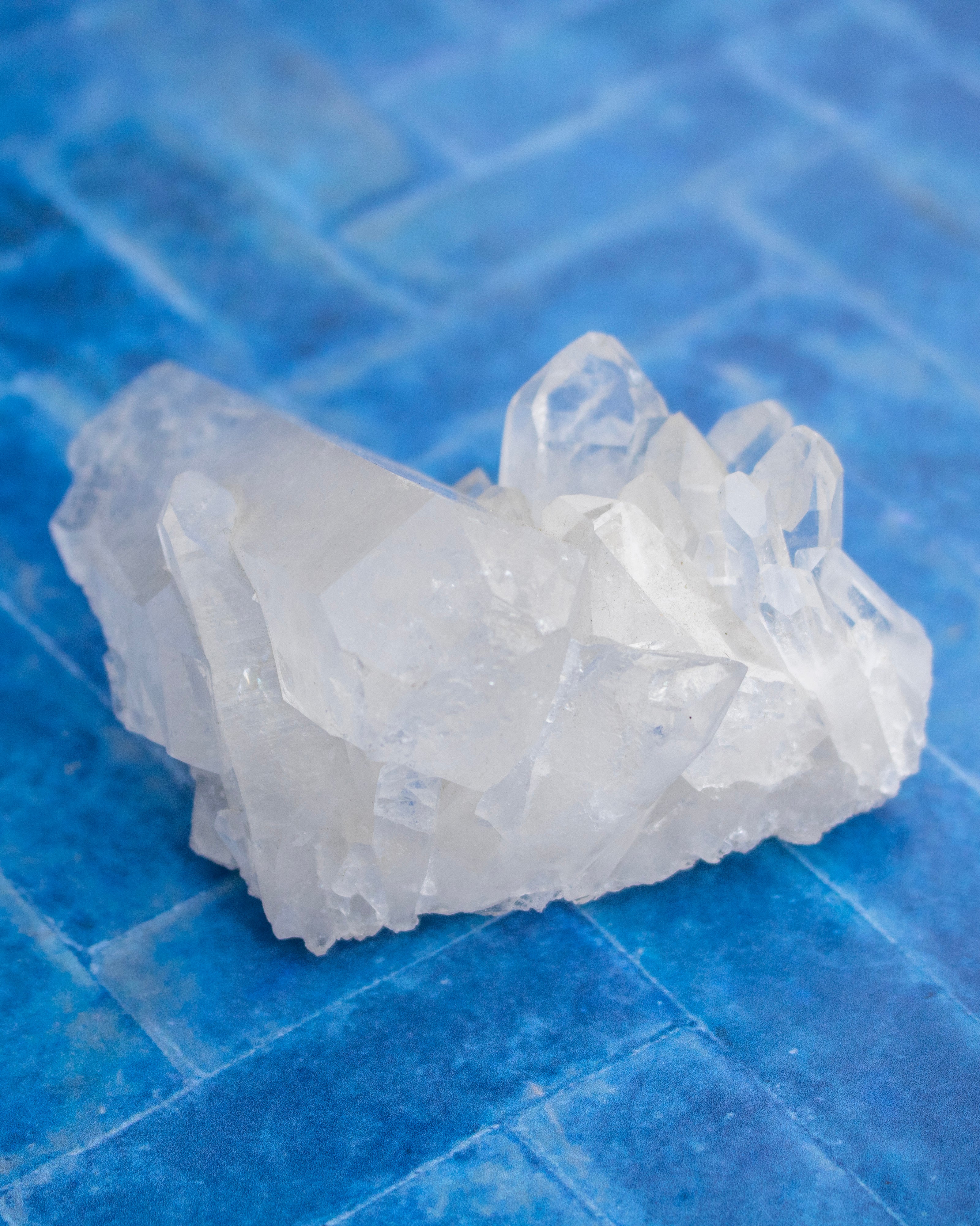 A cluster of translucent white crystal formations resting on a textured blue tiled surface.