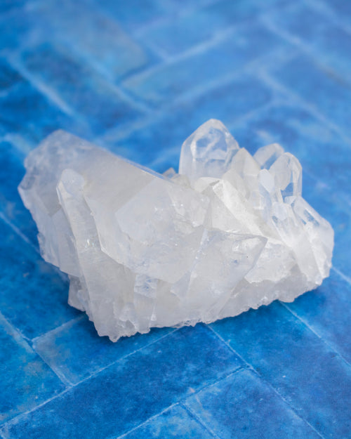 A cluster of translucent white crystal formations resting on a textured blue tiled surface.