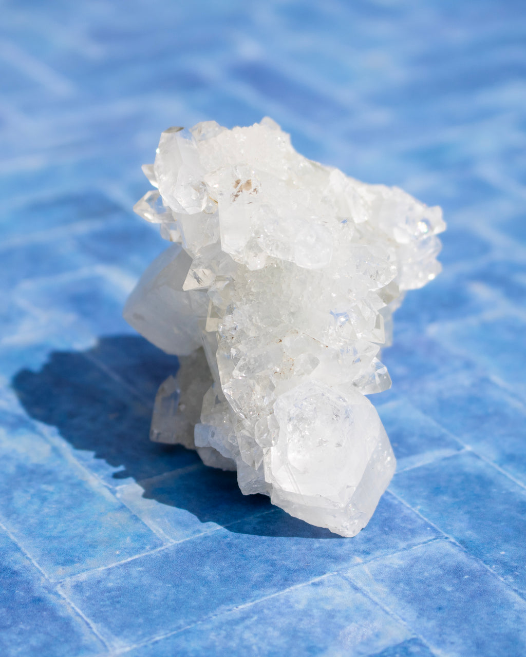 A cluster of translucent white crystals resting on a blue tiled surface.