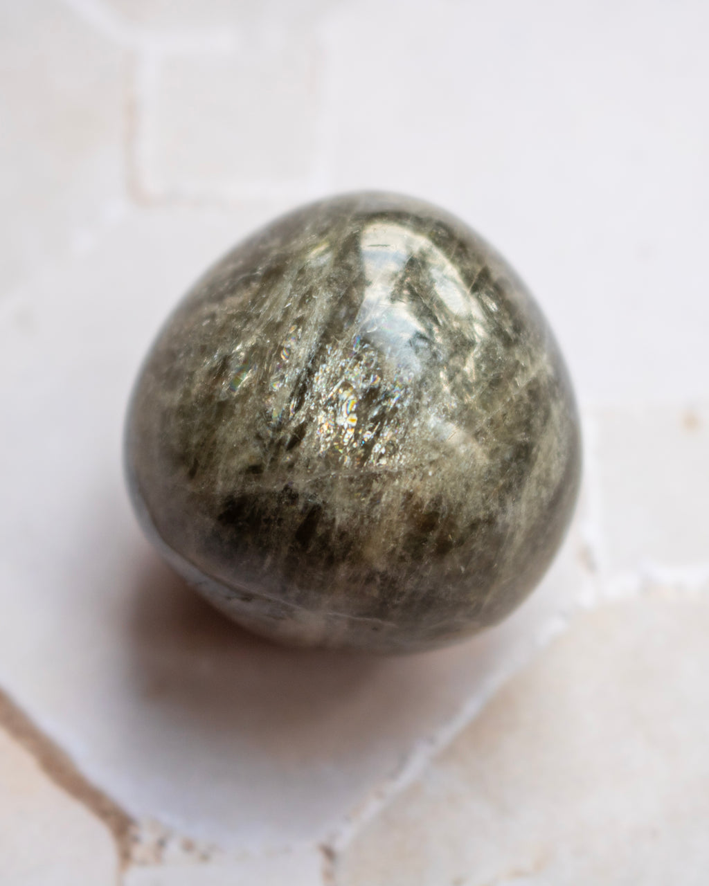 A polished metallic gold bar, likely a gold leaf ingot, resting on a light beige textured stone surface.