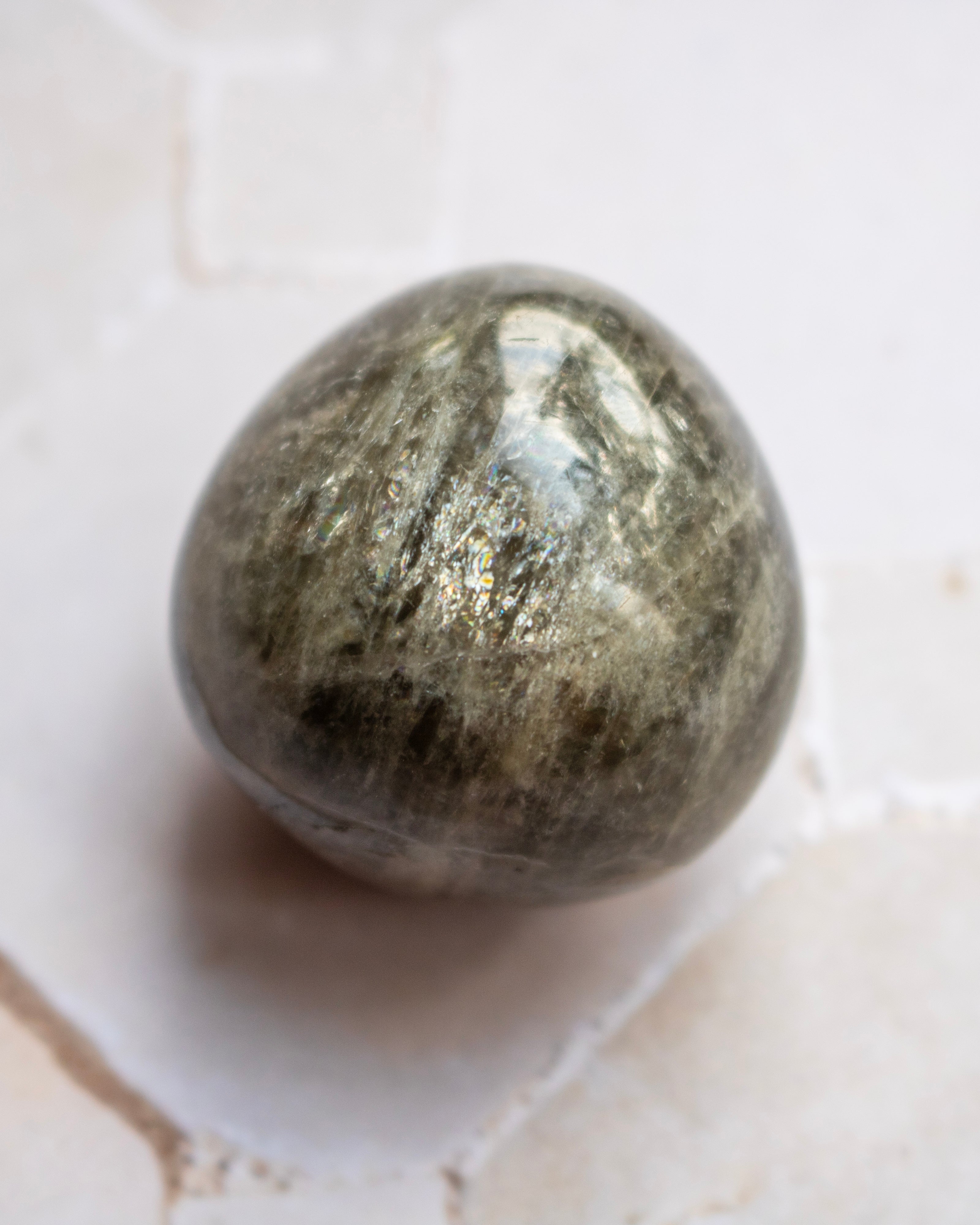 A polished metallic gold bar, likely a gold leaf ingot, resting on a light beige textured stone surface.