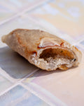 A close-up of a sliced geode specimen showing its crystalline interior and textured outer layers, resting on a glossy tiled surface.