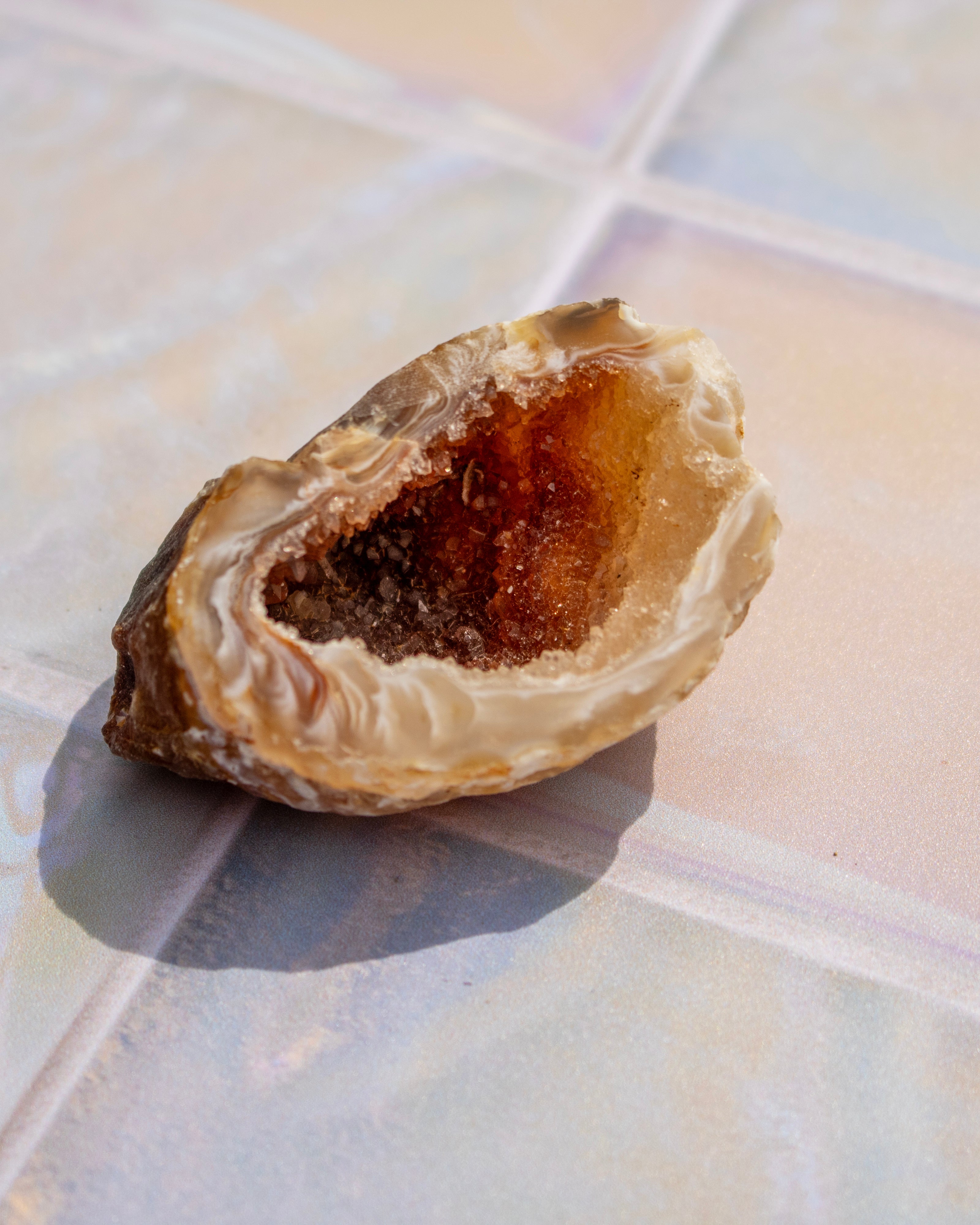 A natural oyster shell geode with a brown crystal interior, resting on a light-colored tiled surface.